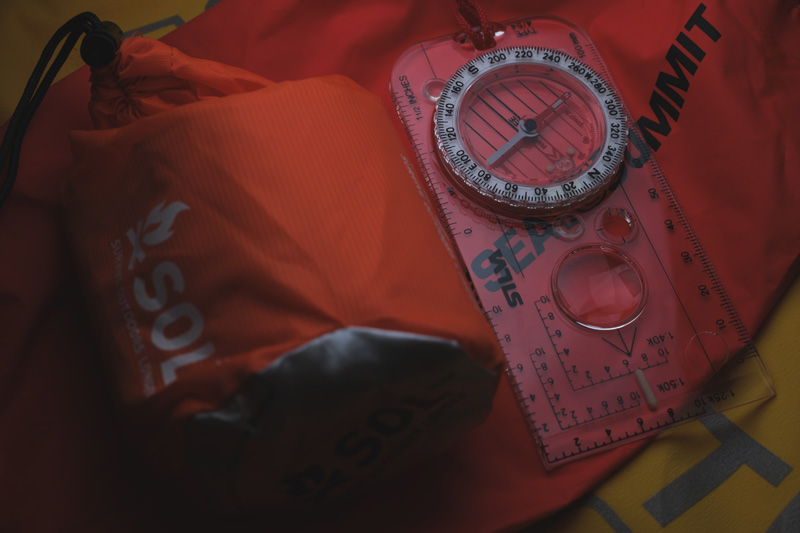 A compass, shelter and dry bag as part of an emergency kit.